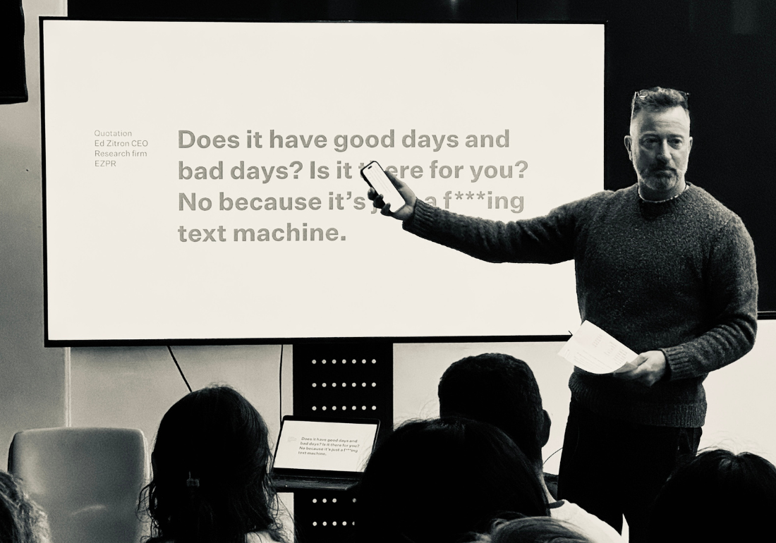 man presenting in front of a screen holding a phone