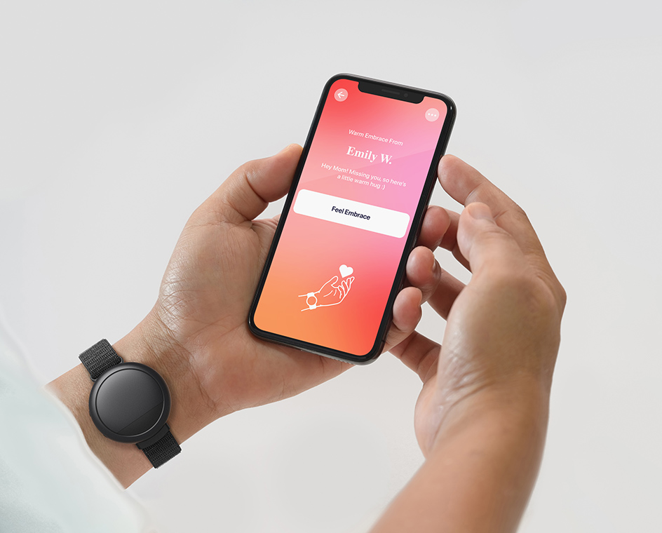 A person wearing a black Embr’s wave on their wrist holding a phone with the Wave app open on it
