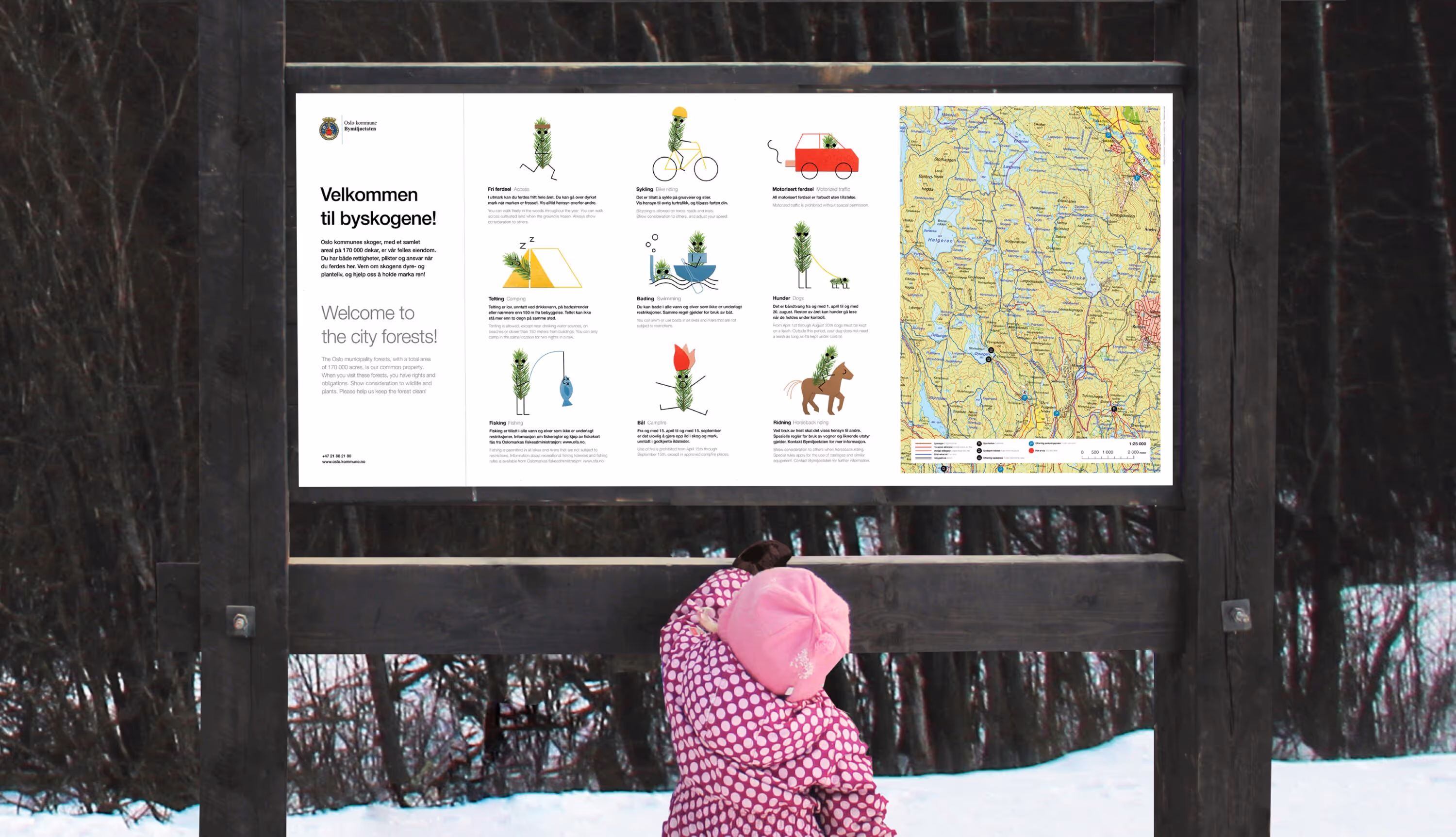 Child in pink jacket and hat pointing at a large city forest information board with map and rules in snowy wooded area.