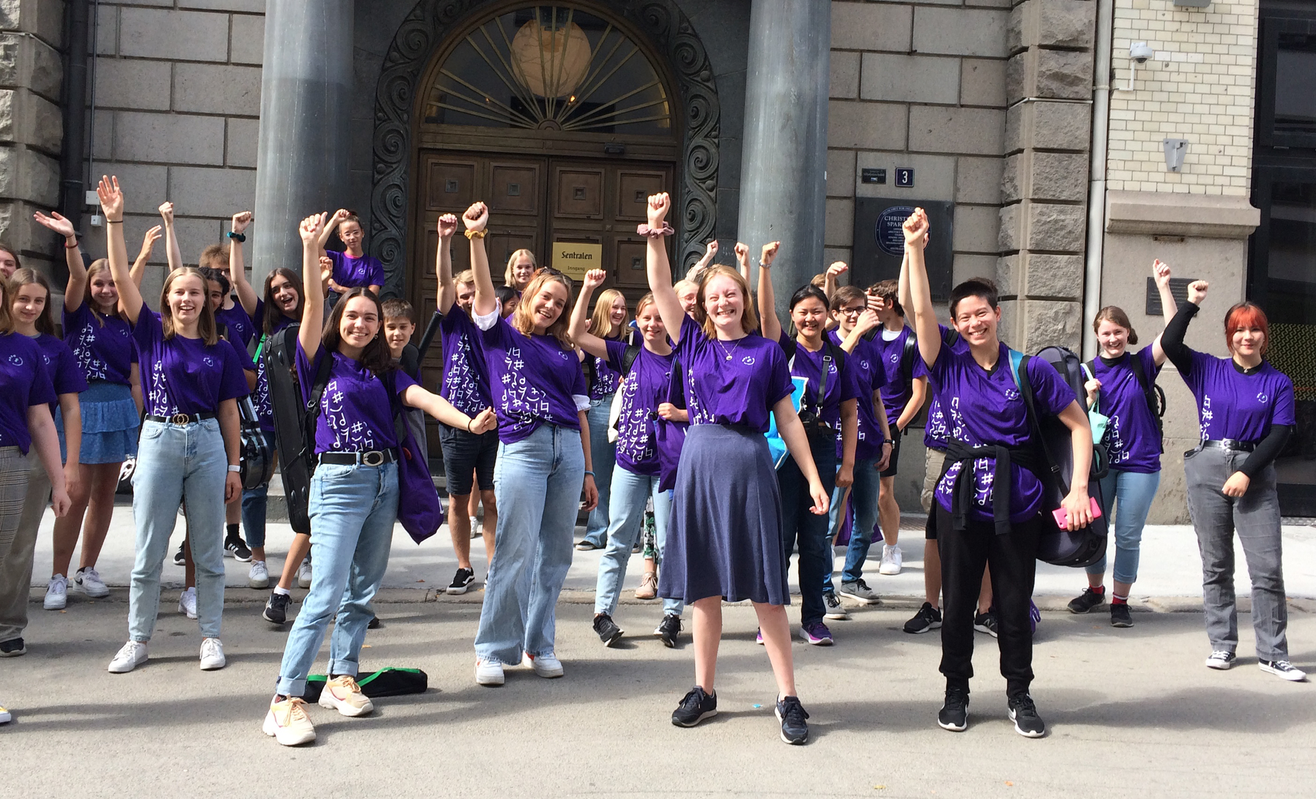 A group of people in purple NUSO shirts standing in front of a building.