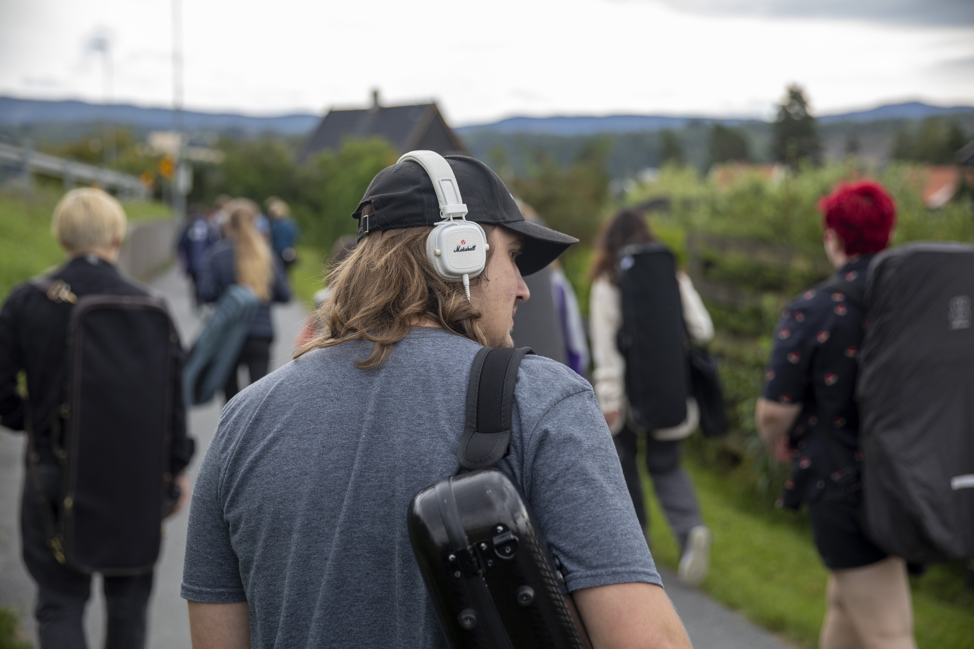 A group of people walking down a sidewalk while carrying instruments.