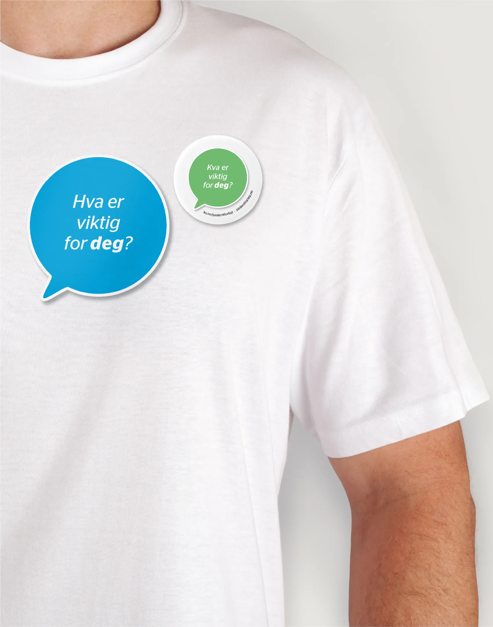 Close-up of a person wearing a white t-shirt with two speech bubble stickers on it, one blue and one green, with Norwegian text reading 'Hva er viktig for deg?'