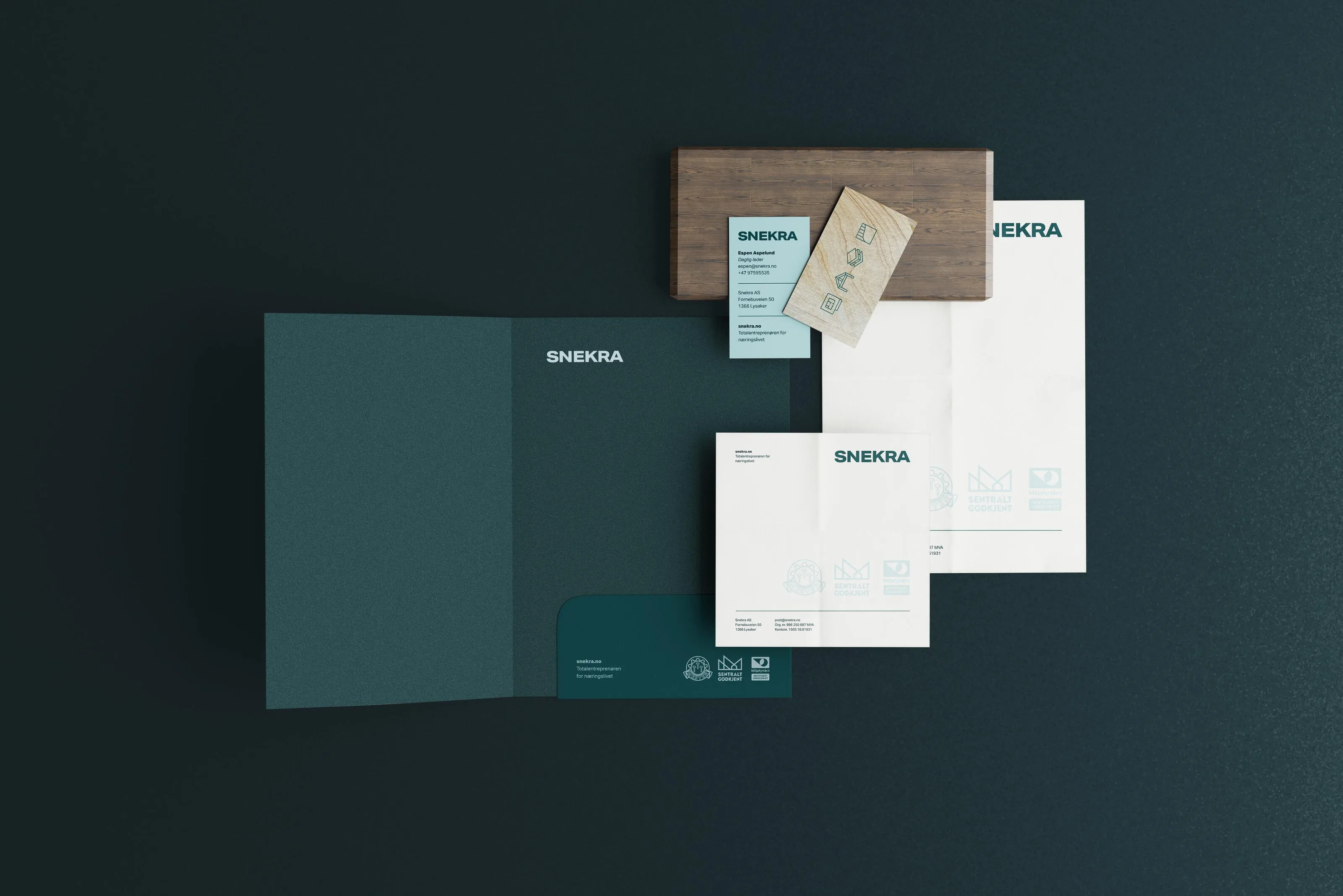 Set of branded stationery including folder, business cards, envelopes, and letterhead with the name SNEKRA on a dark background.