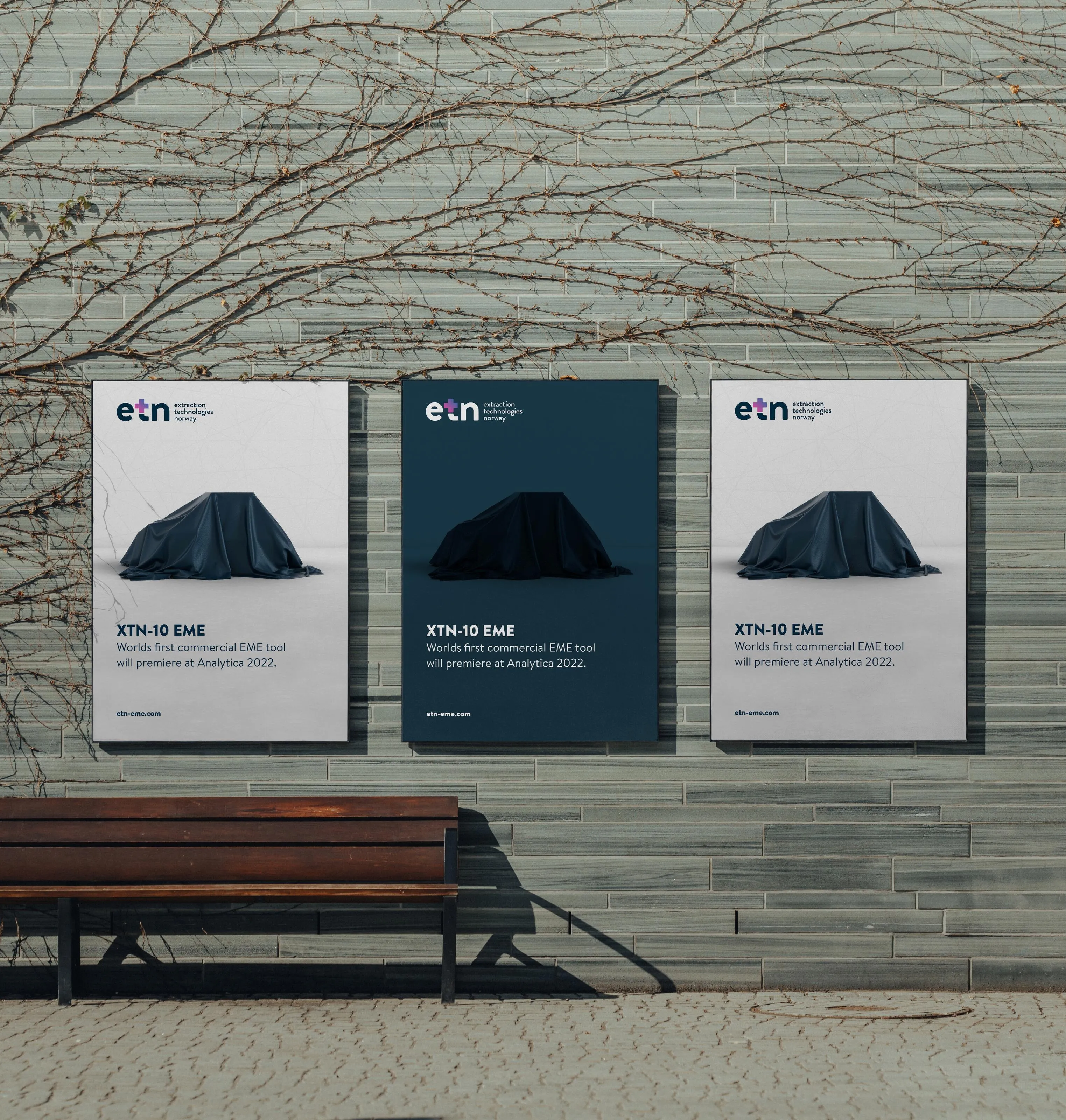Three ETN posters on a wall with the text 'XTN-10 EME Worlds first commercial EME tool will premiere at Analytica 2022', featuring a dark cloth-covered object.