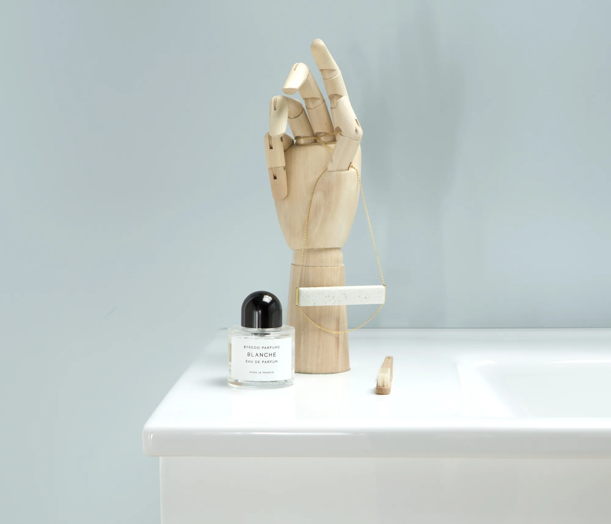 White bathroom vanity unit with light wood cabinet doors and chrome taps, set in a bright Nordic bathroom with white tiles and natural light from a window.