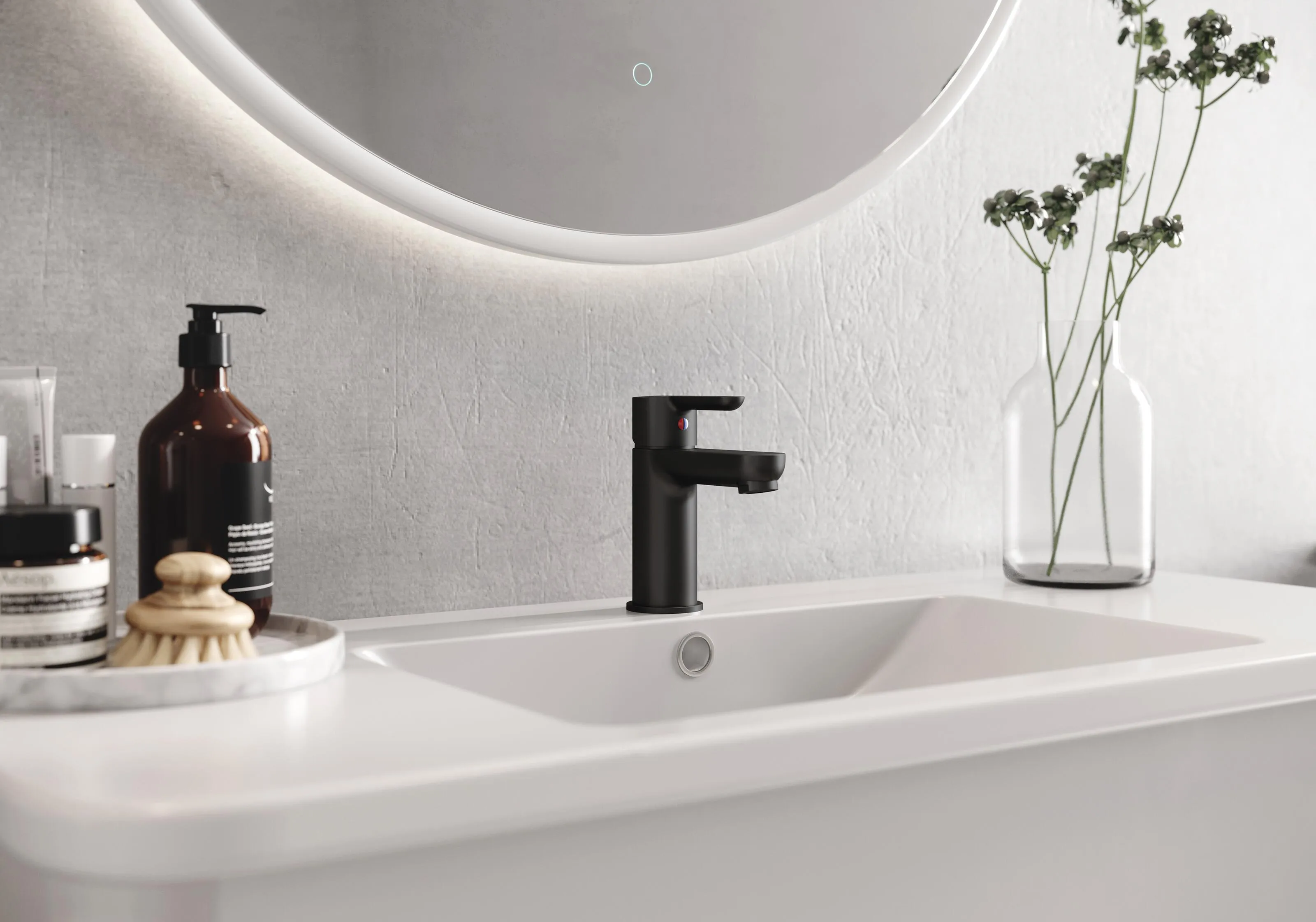 A bathroom sink with a soap dispenser and a round mirror.