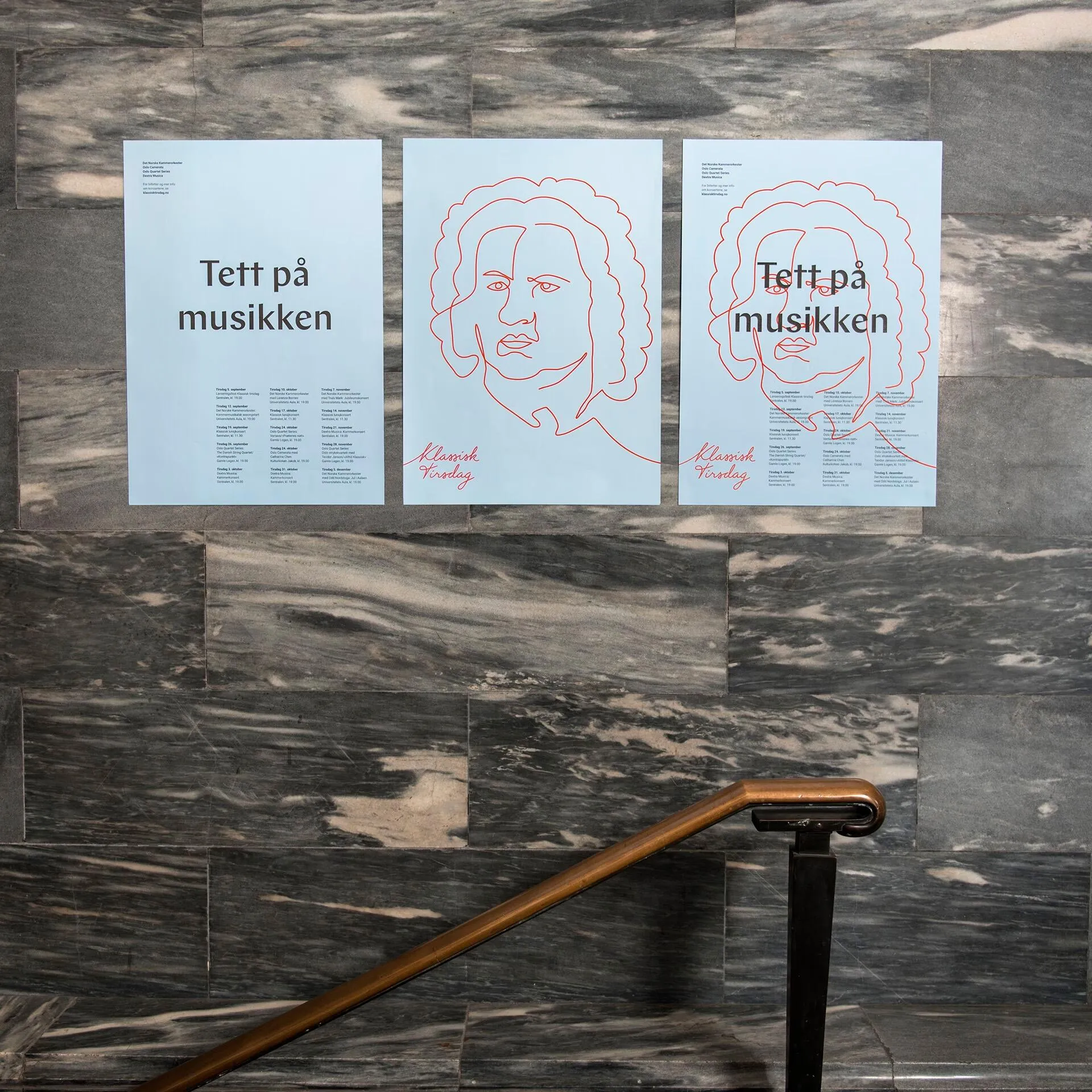 Three light blue posters on a gray marble wall, featuring text in Norwegian and red line drawings of a classical composer’s face.