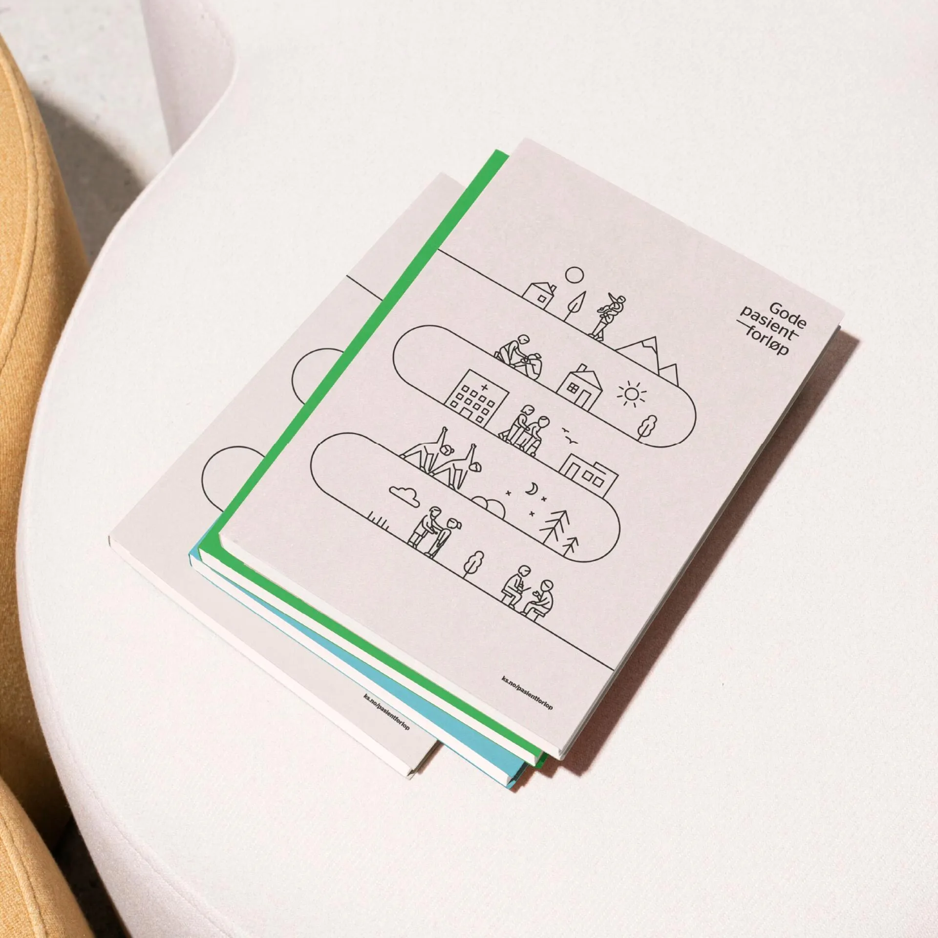 Stack of three books with simple line illustrations depicting healthcare and daily life scenes on the top book, placed on a white table.