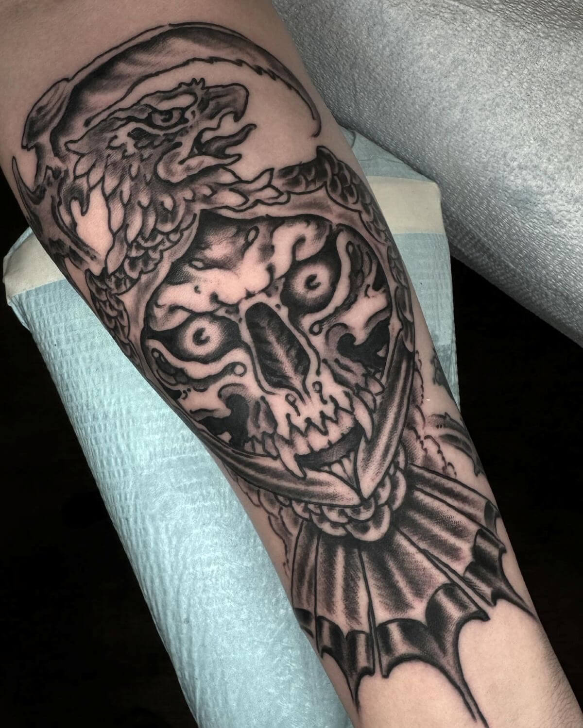 Black and grey fanged skull with eagle head and scythe.