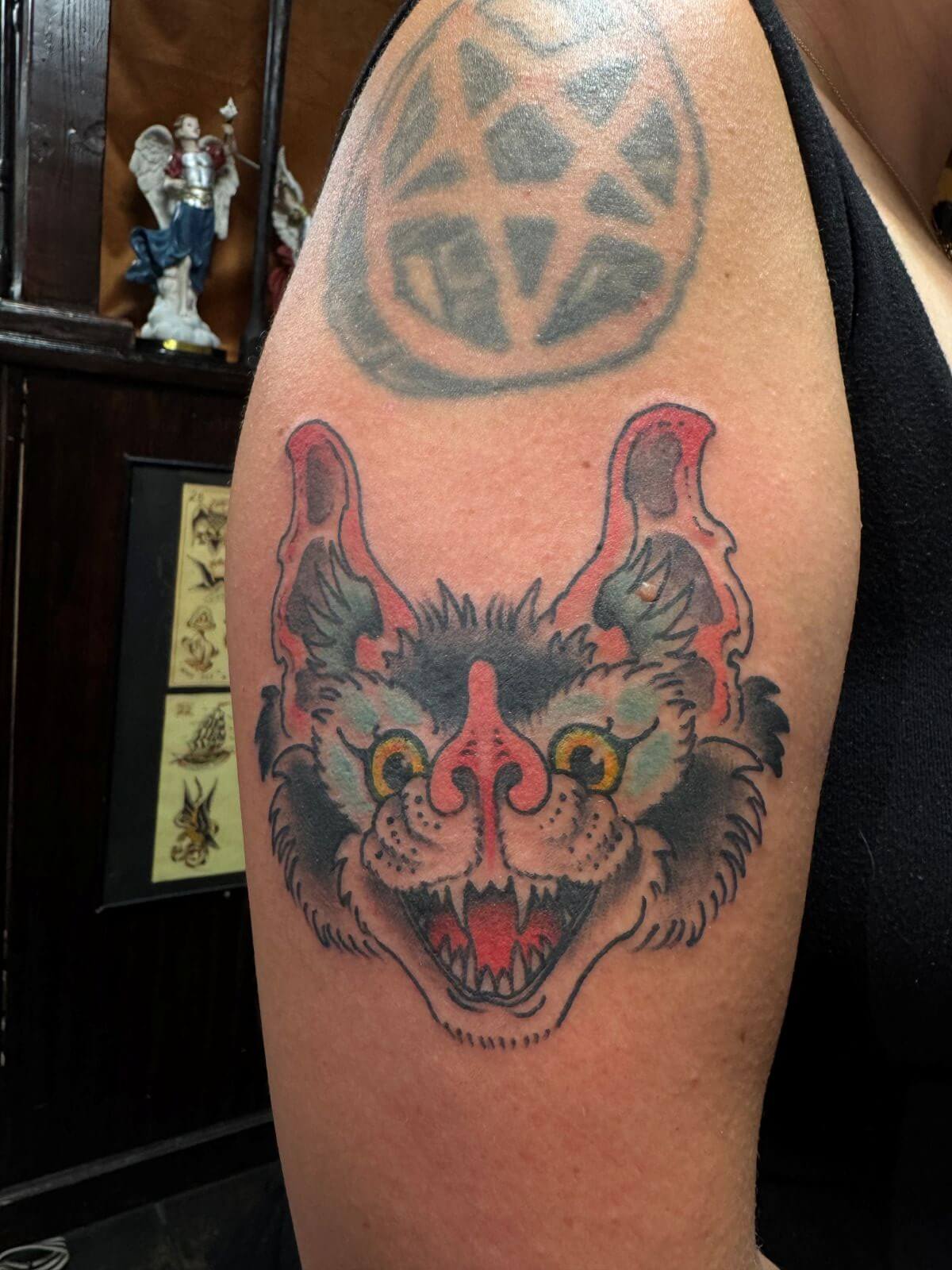 Open-mouthed black, blue, and pink bat head tattoo