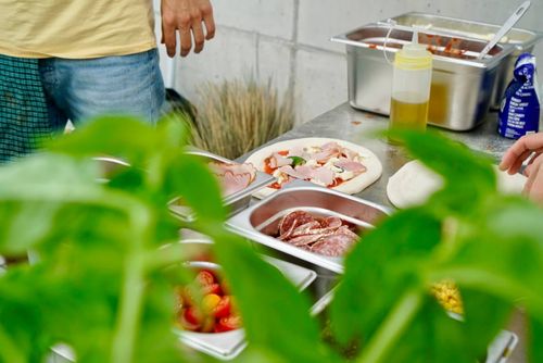 Pizza wird zubereitet. Frische Zutaten in Behältern.