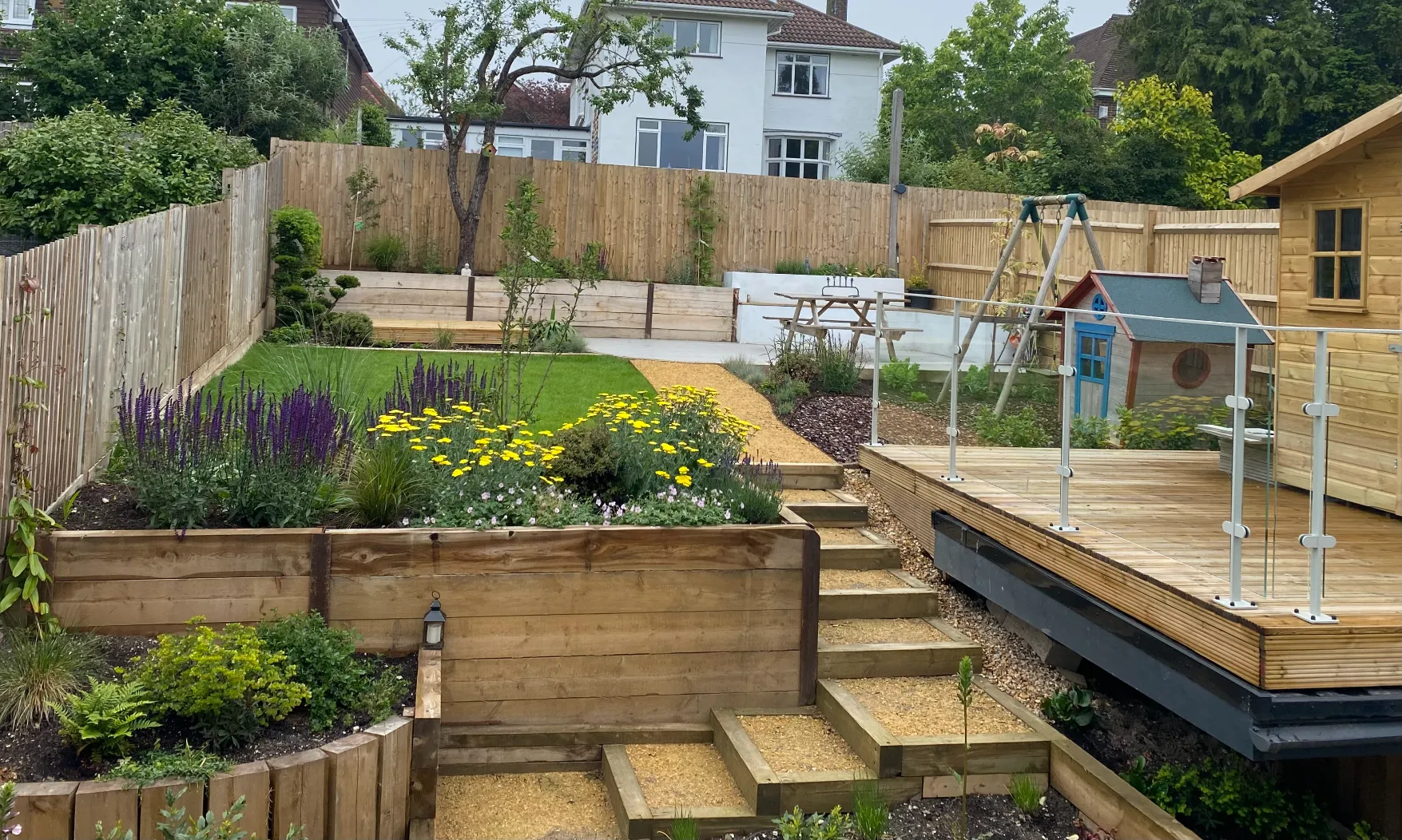 Terraced garden design in Sussex with levelled planting beds, local stone and multiple outdoor zones