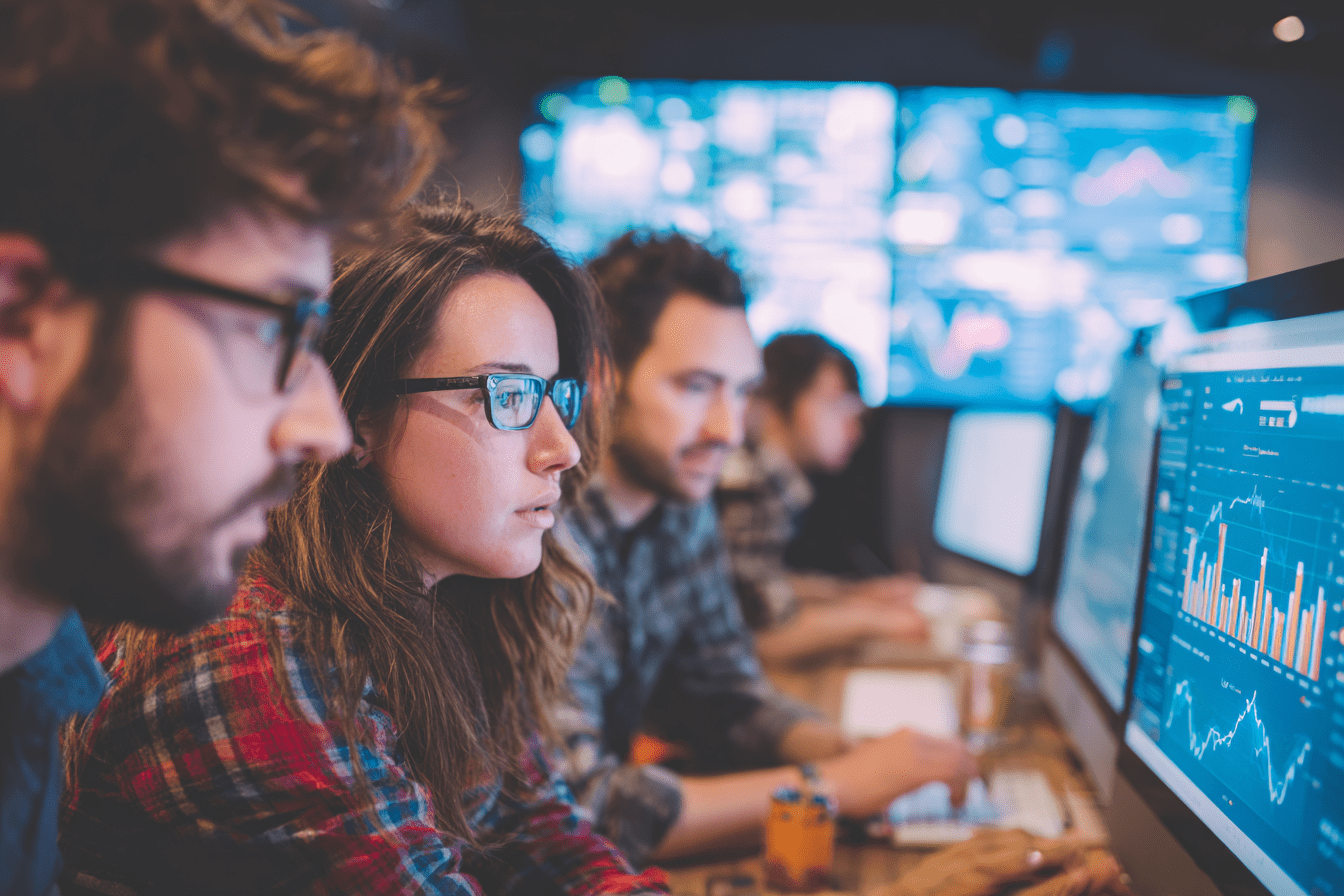 A team of digital marketers analyzing campaign data on multiple screens to measure growth for a tech company