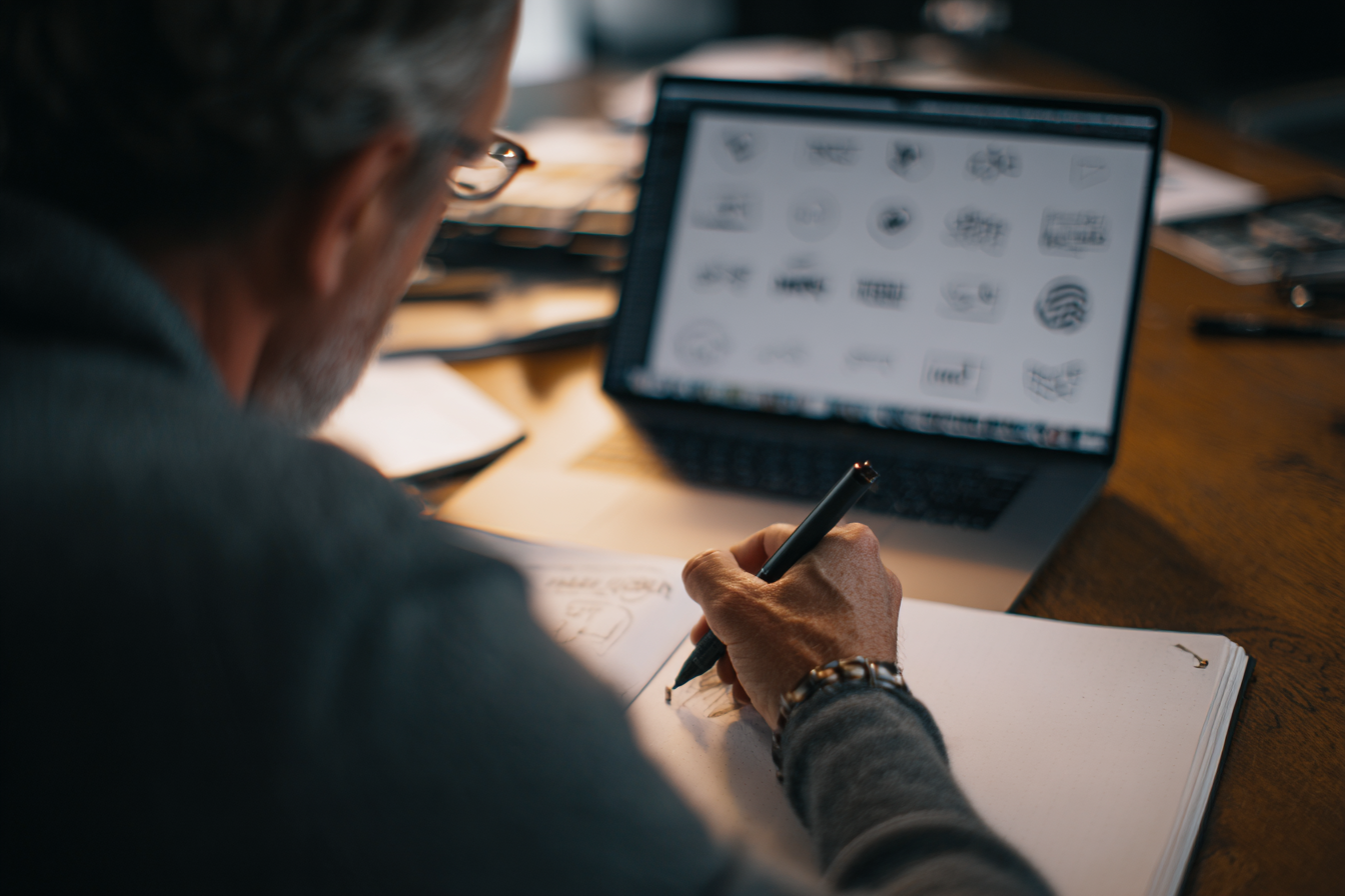 MSP founder reviewing multiple MSP logo concepts on a laptop with a designer