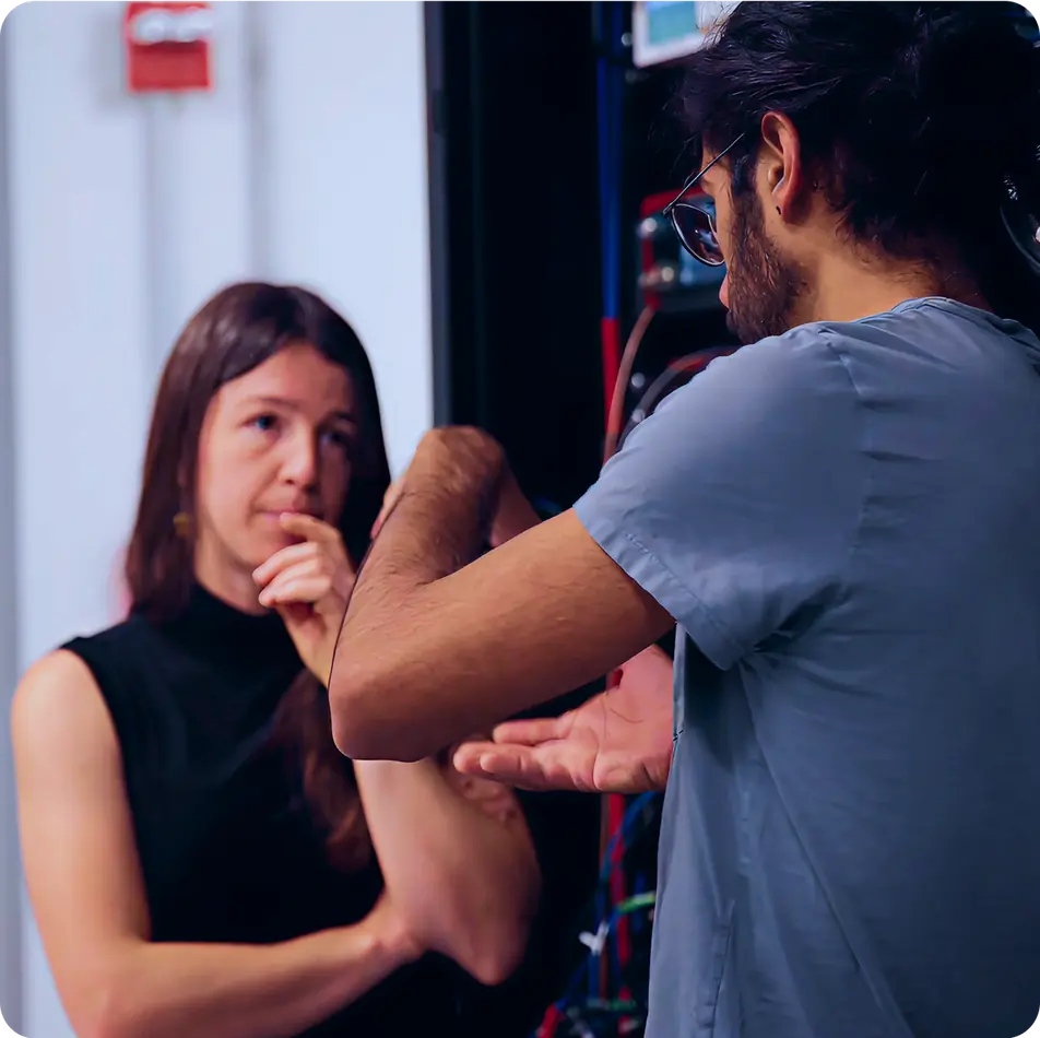 Two individuals engaged in a focused discussion, with one explaining and gesturing while the other listens thoughtfully.