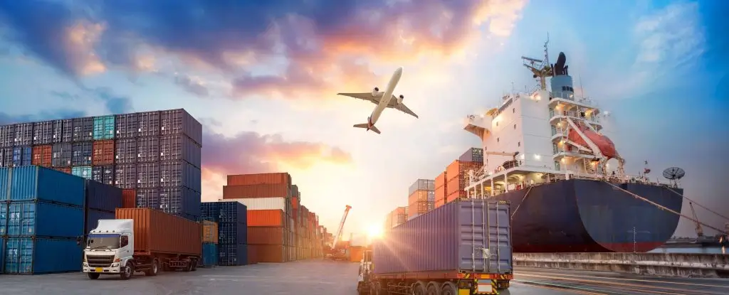 A busy shipping port at sunset with cargo containers and an airplane in the sky