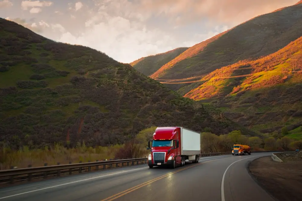 red truck driving through a picturesque mountainous landscape during sunset