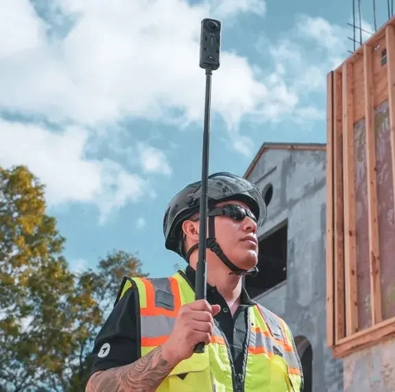 Construction worker in safety vest and helmet holding a 360 walkthrough camera for ground walks on a construction site