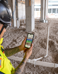 A man looking at a phone on a construction site