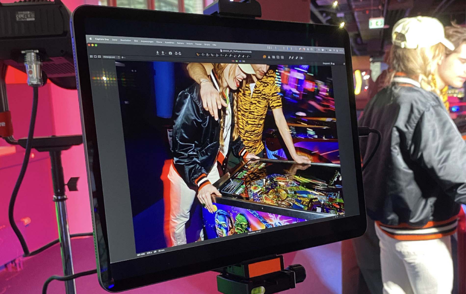 Photo of a tablet showing two people laughing while they play with a pinball machine, the shot is part of the marketing campaign