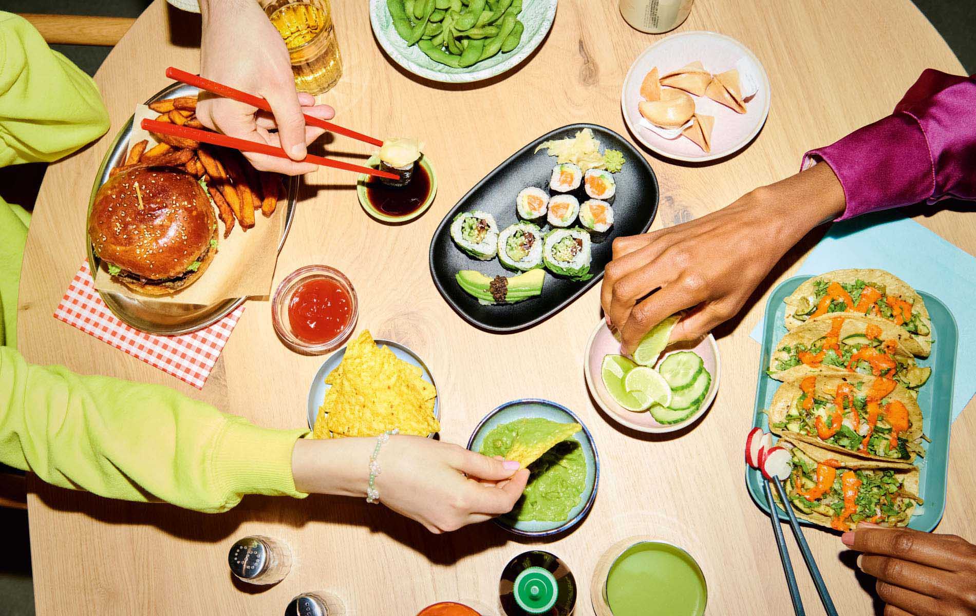 A top-down image of a wooden table set with a variety of foods and dishes, the shot is part of the marketing campaign