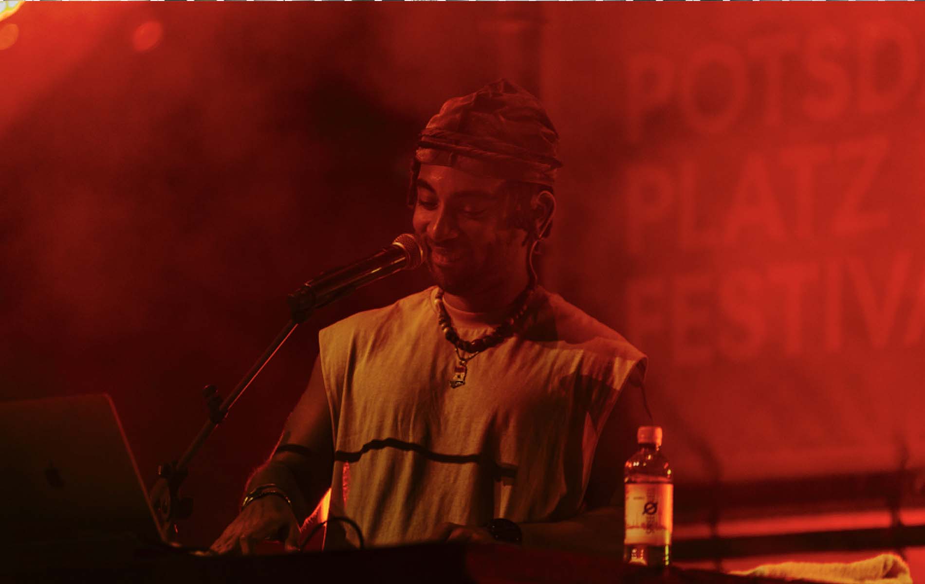 An artist on a stage with a microphone with the Potsdamer Platz brand design in the background