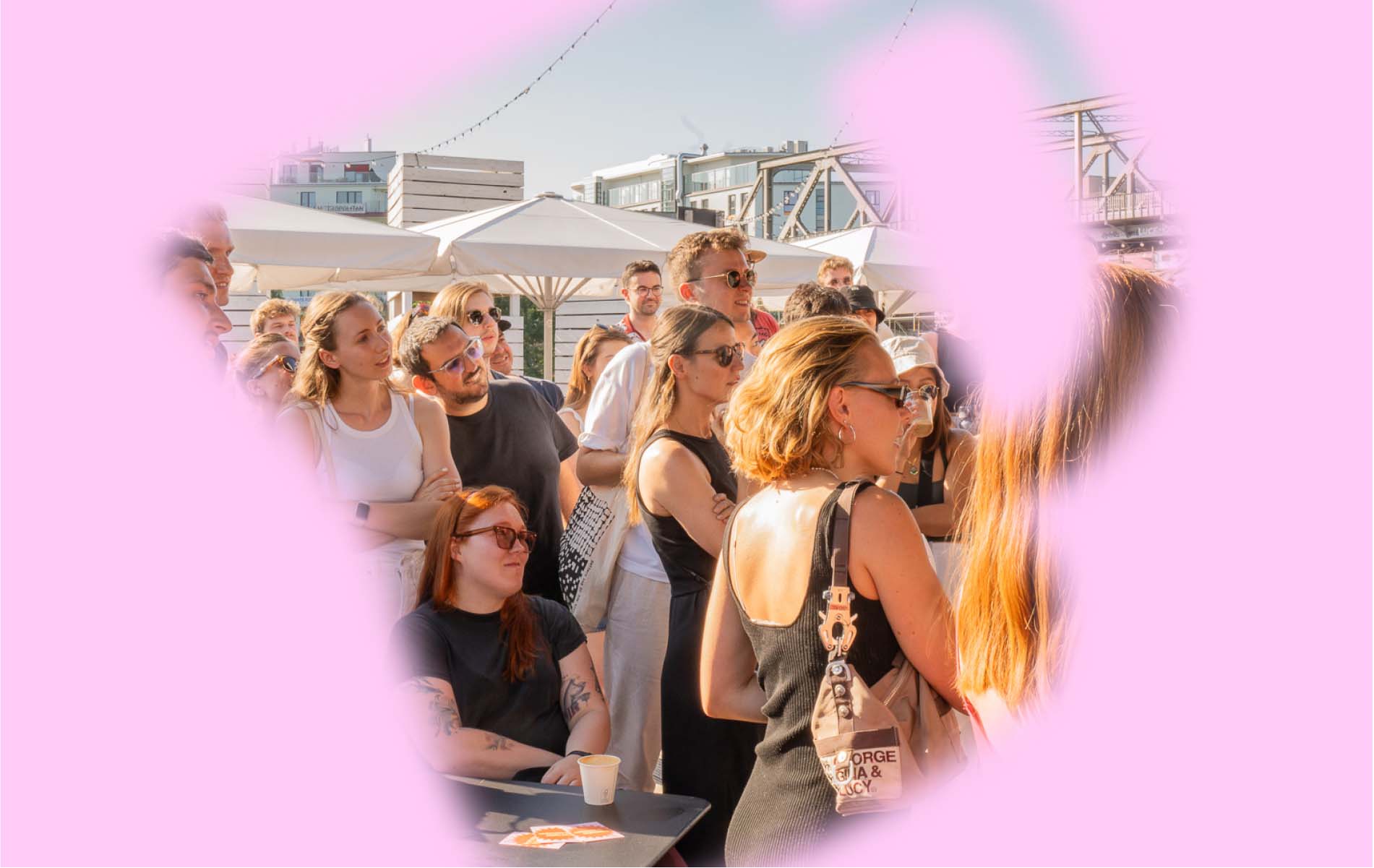 A crowd of people all looking to the same directions and listening to a speech, a pink layer covering some parts of the image is added to the picture 