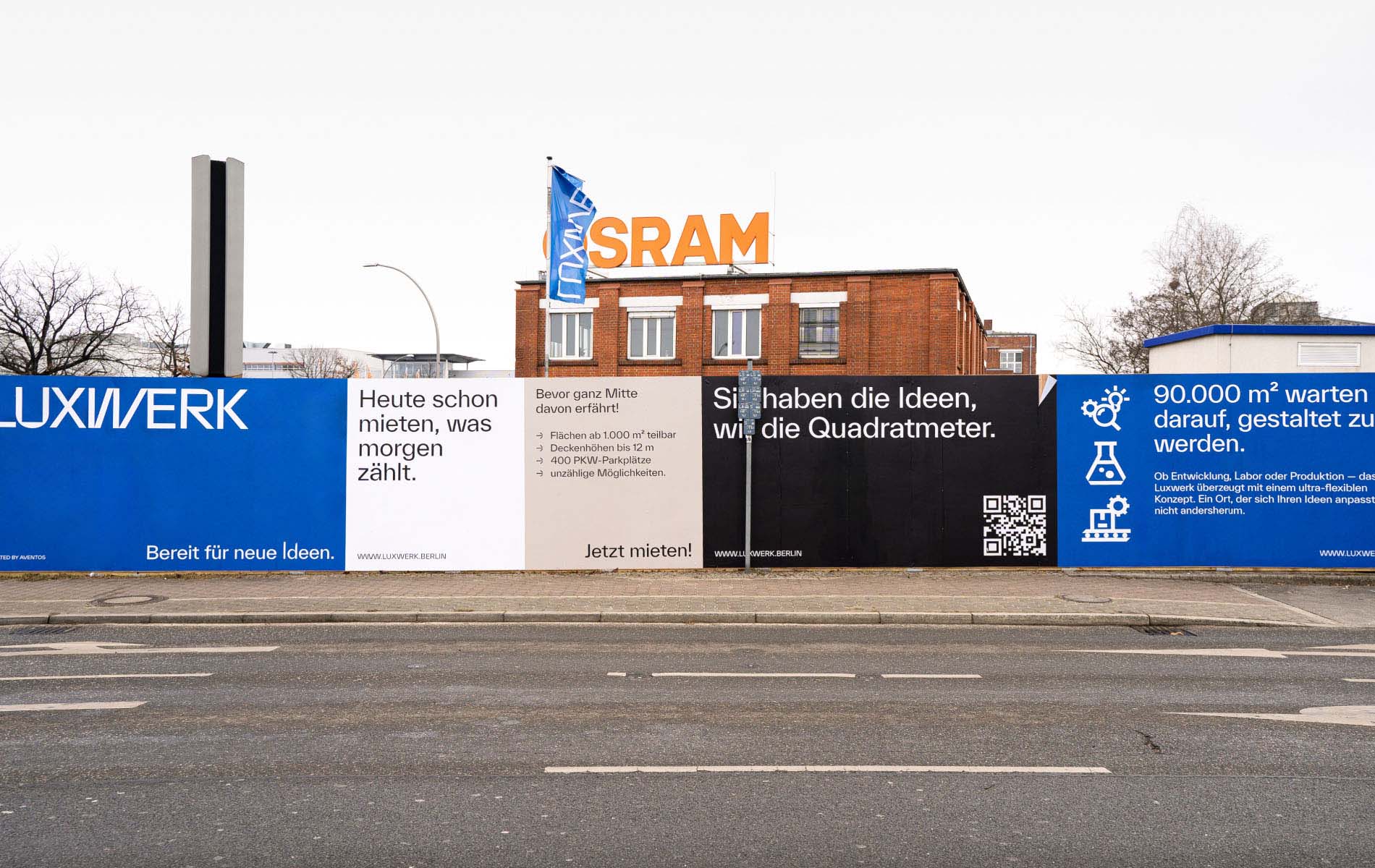 Photo of advertising banners for Luxwerk on a street. It reads "Heute schon mieten, was morgen zählt. - Sie haben Ideen, wir die Quadratmeter"
