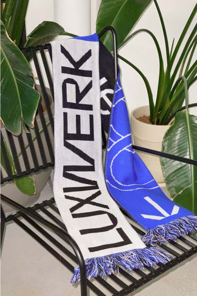 Luxwerk branded scarf in blue, white and black colors on a chair with plants in the background, as part of the brand identity design