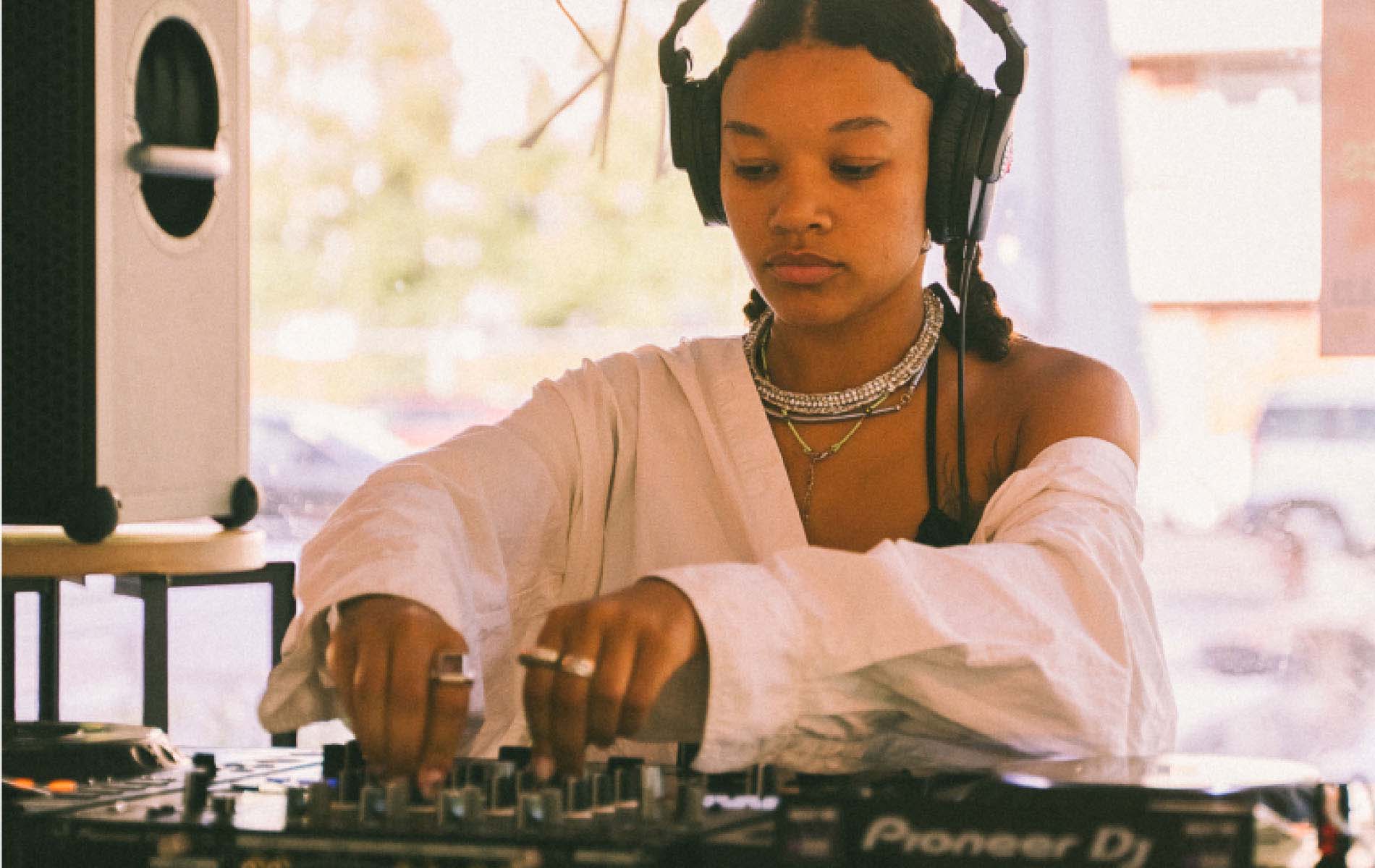 A DJ wearing headphones and manipulating the sound booth 