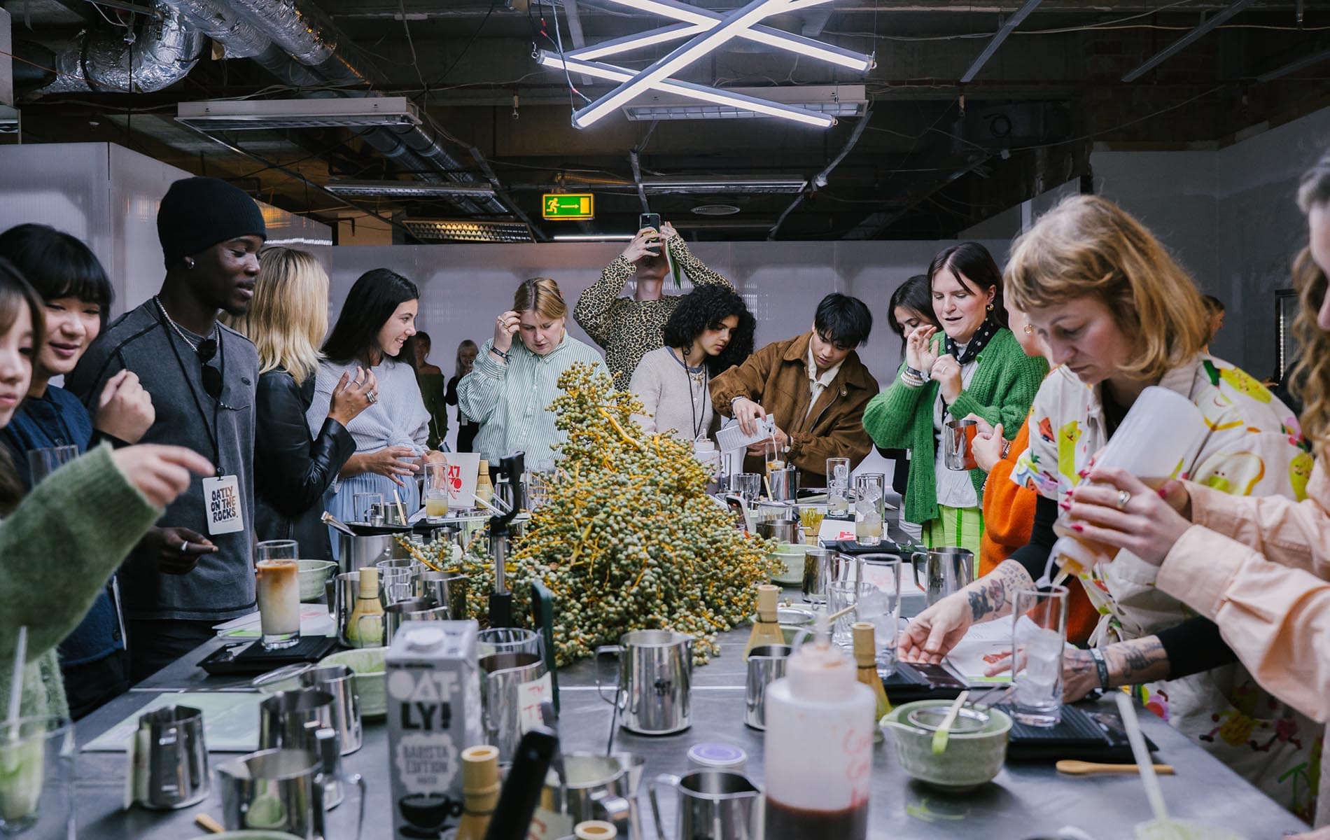People gathered around a workshop table mixing drinks at an Oatly event, captured by a creative agency, design studio, and branding agency in Berlin.
