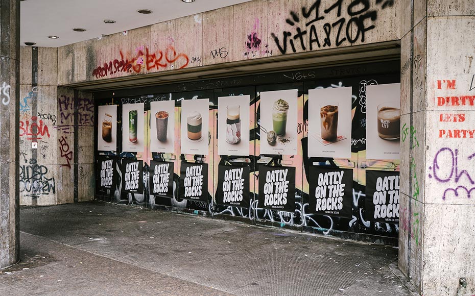 Posters of Oatly drinks displayed on a graffiti-covered Berlin storefront, captured by a creative agency/design studio.