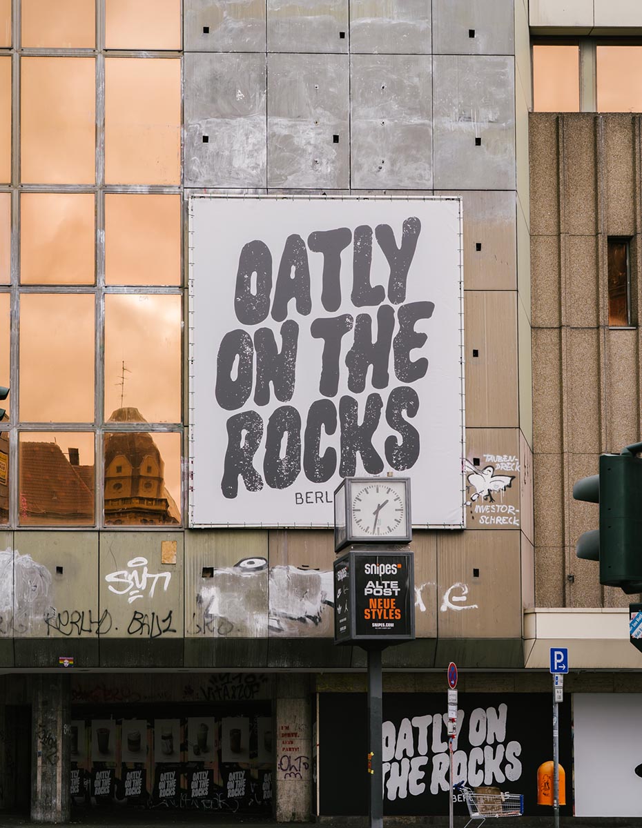 A large “Oatly On The Rocks” billboard on a worn Berlin building, photographed by a creative agency and branding agency.