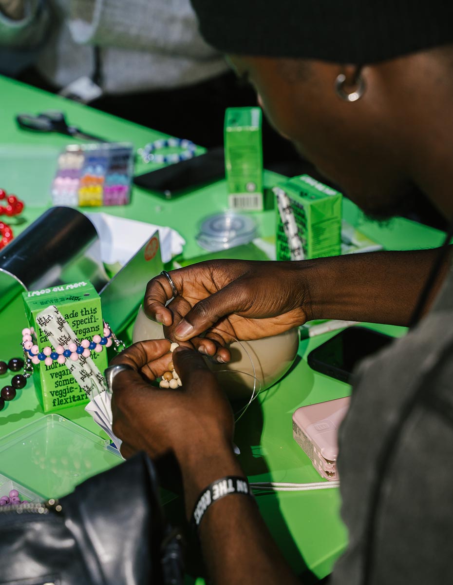 Close-up of hands threading beads at an Oatly workshop table, photographed by a creative agency/marketing agency in Berlin.