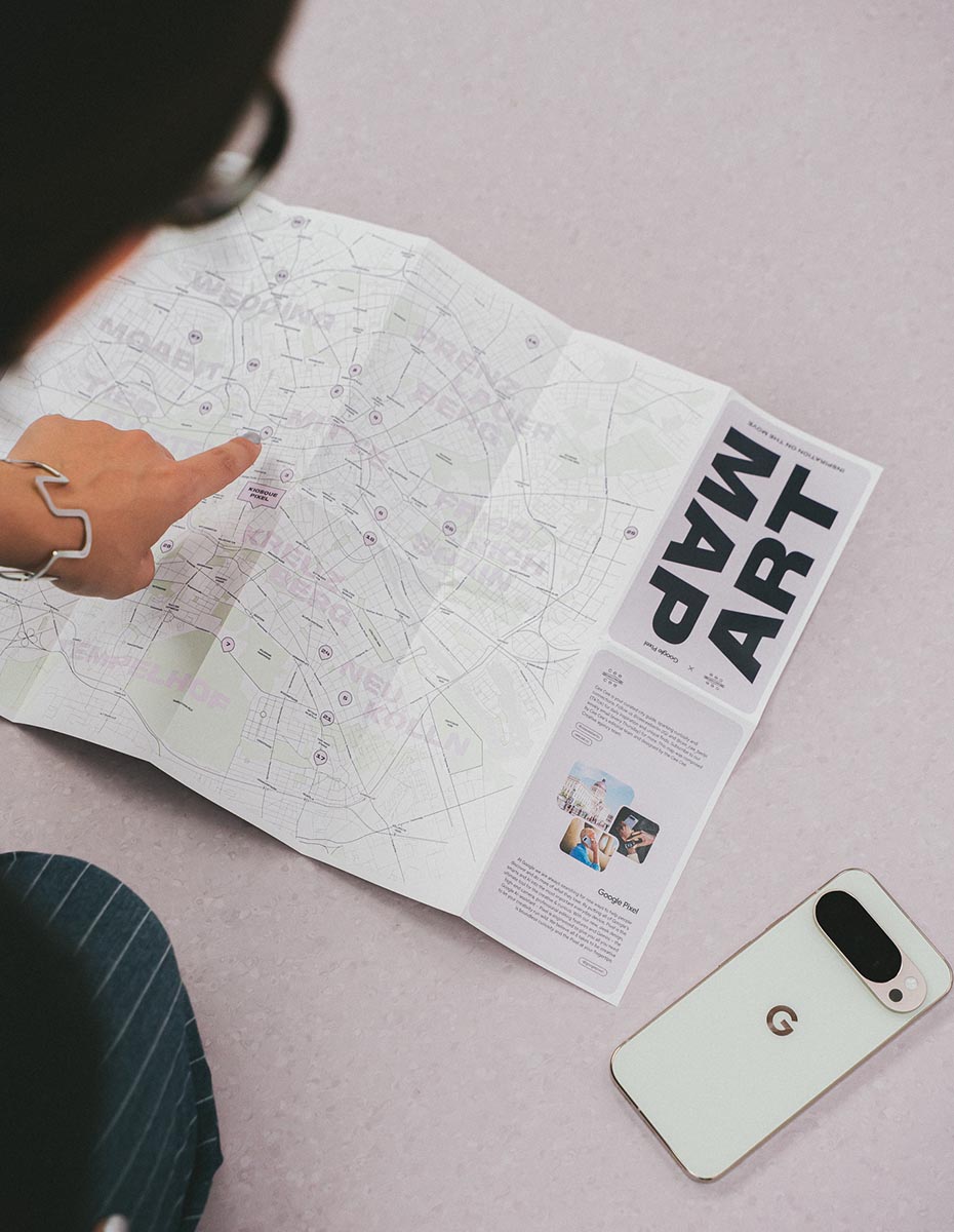 A close-up of an art map on the floor with a hand pointing to a location, produced by a Creative Agency specializing in UX Design, Illustration, and Content-Writing for brand communication.