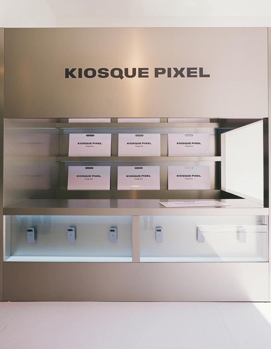 A minimalistic display at “Kiosque Pixel” with product boxes and devices.