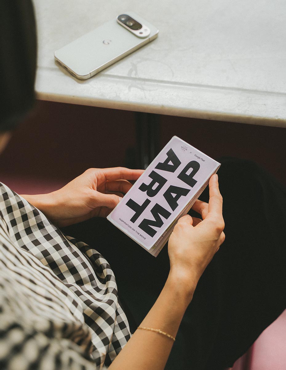 Person holding a folded art map with a Google Pixel phone on the table, photographed by a Creative Agency for Social Media Content and Branding.