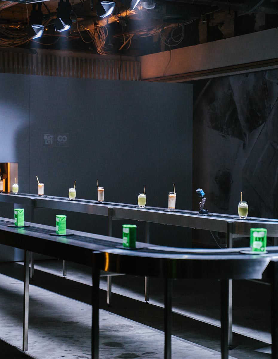 A row of Oatly Matcha drinks displayed on a conveyor-style table at the launch event, photographed by a creative marketing agency and branding agency in Berlin.