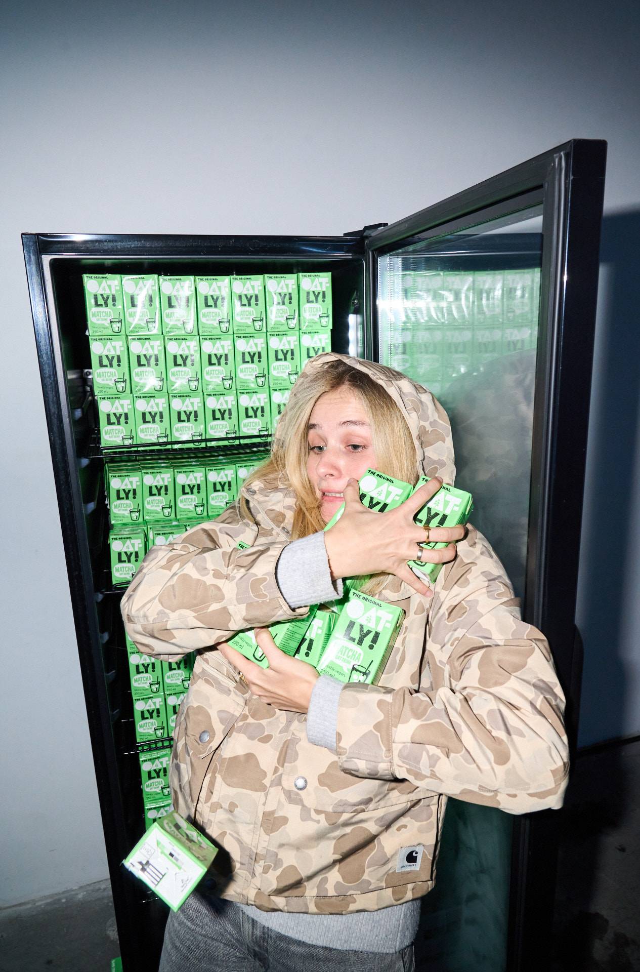 A guest at Oatly’s matcha launch party holding a cup of iced matcha latte in front of a branded backdrop, photographed at the Cee Cee Creative–organized event.