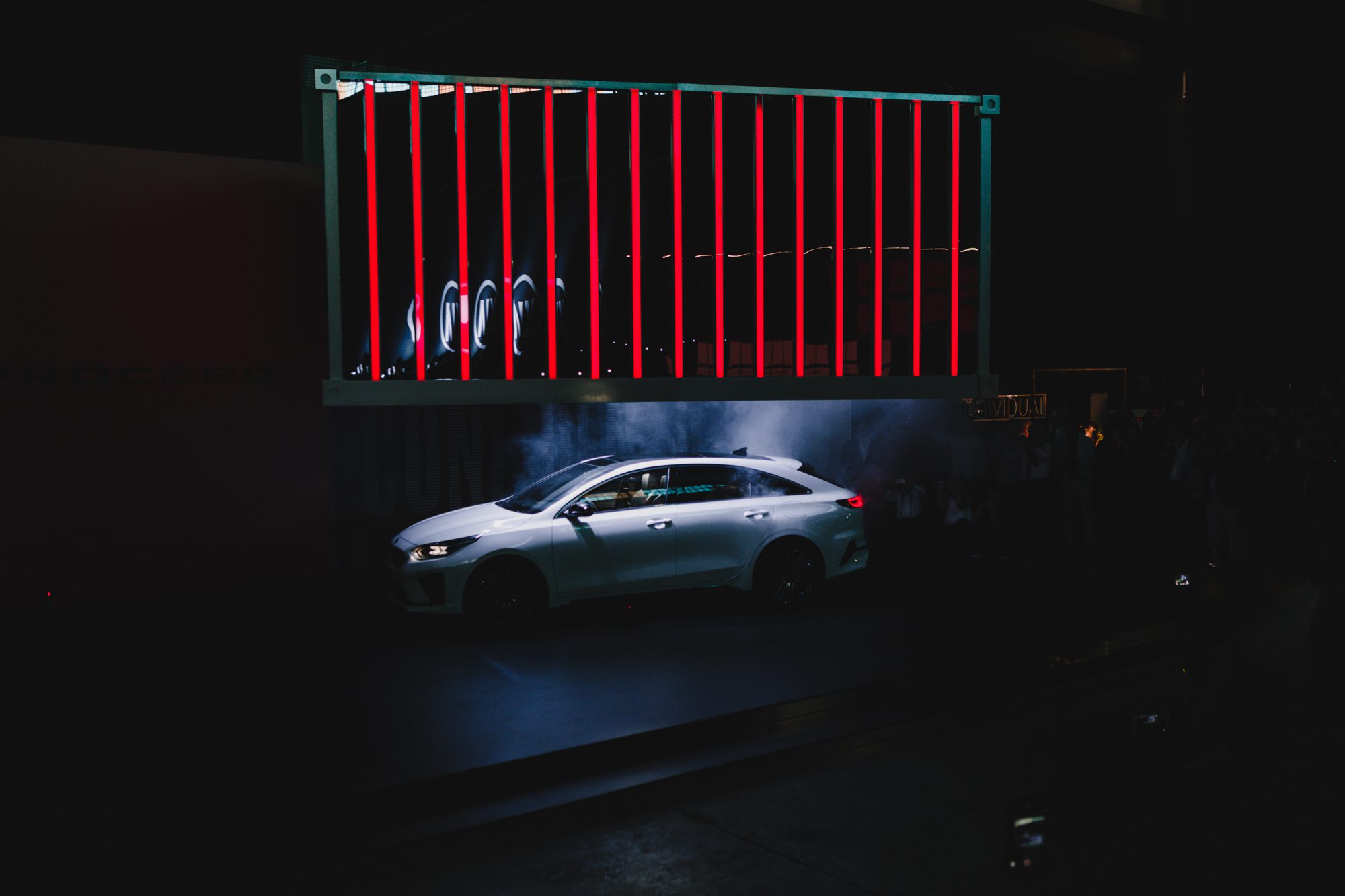 A photograph of the revealing moment of the KIA launch event, a container being lifted and showing the new car.
