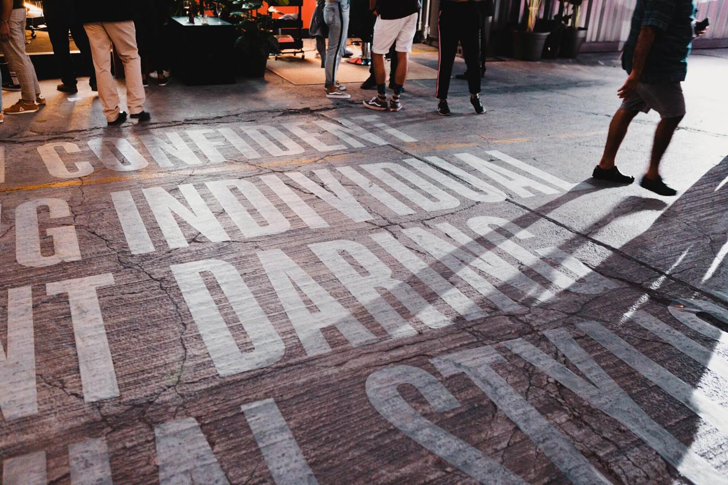 A photograph of the graphic design for the floor, showing a concrete floor and bold white typography.