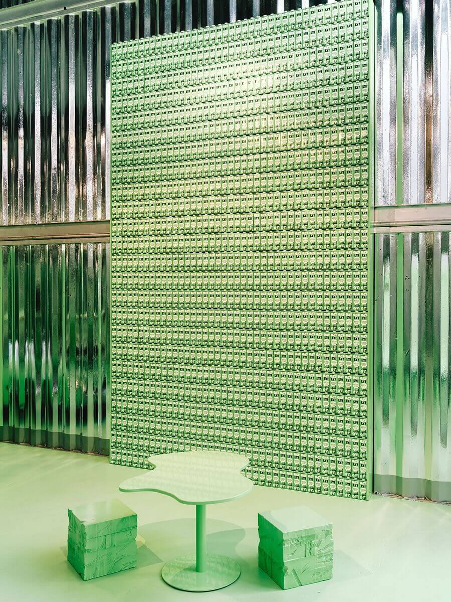 Wall panel made of repeated Oatly packaging pattern with seating – corporate identity brought into physical space
