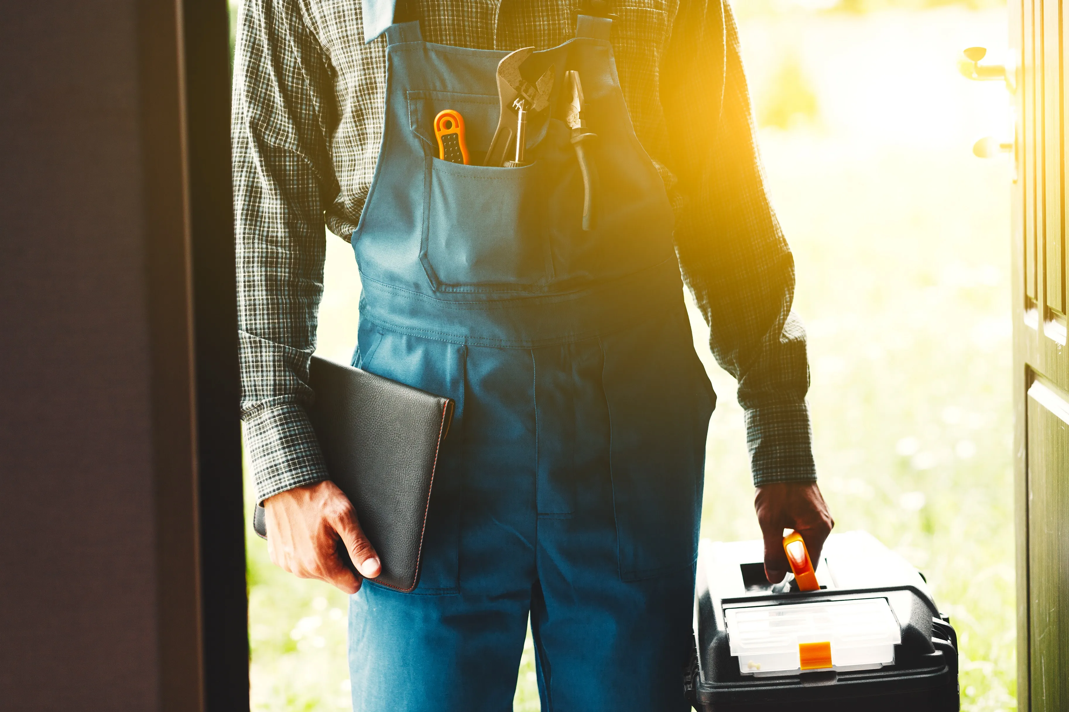 photo of a plumber holding a toolbox with the sun filtering through 