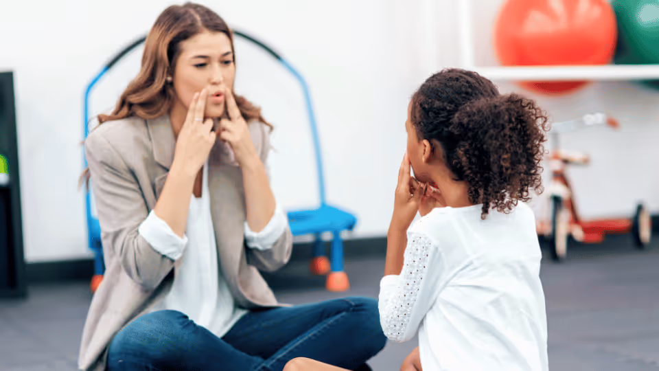 A woman and a young girl are seated on the floor, sharing a moment of connection and warmth together