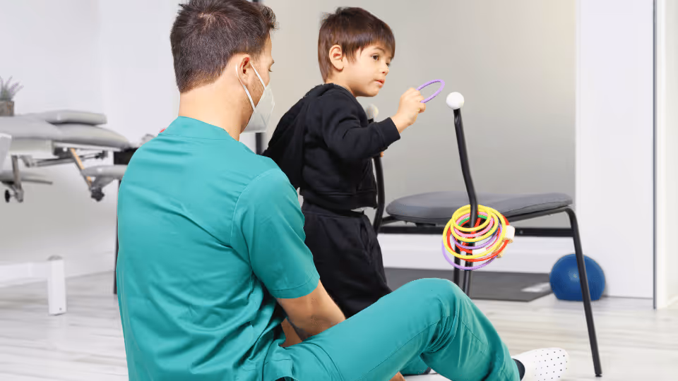 A man and a child in green scrubs joyfully play together with a colorful toy, showcasing a moment of bonding