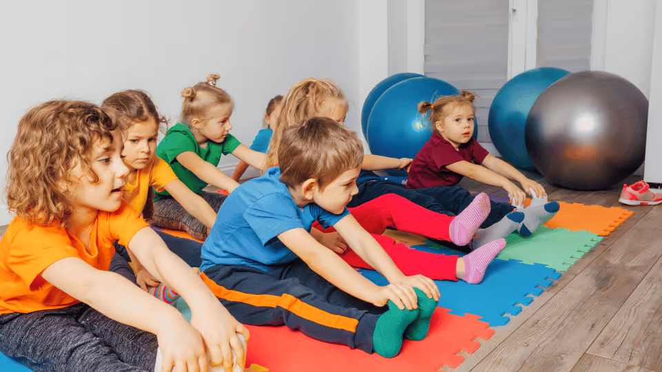 Children seated on colorful mats in a room, engaging with exercise balls for physical activity and play