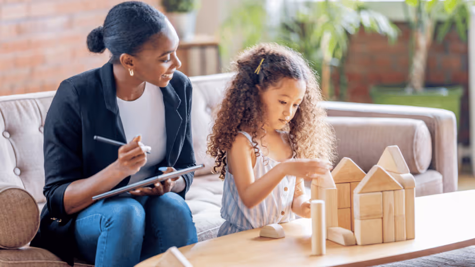 A mother and daughter work side by side to construct a house, exemplifying collaboration and familial support in their endeavor