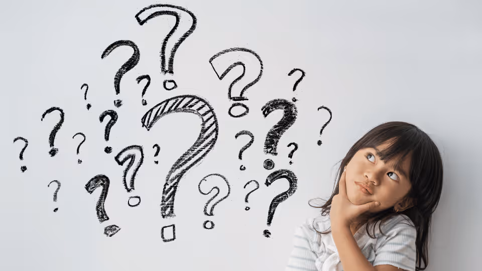 A young girl gazes at a wall filled with question marks, representing her quest for understanding pediatric speech therapy.
