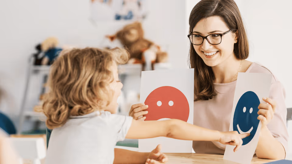 A woman, a speech therapist, and a child display two smiley faces, representing joy and effective communication.