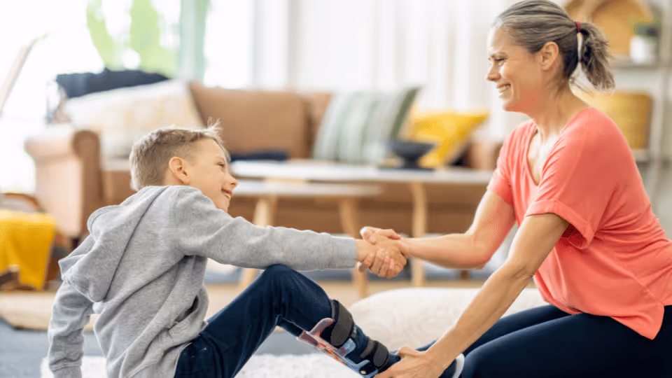 A physical therapist assists a boy with his leg brace during a rehabilitation session, promoting mobility and support.
